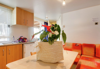 Interieur van de Luna Pineta stacaravan in Italië met gezellige keuken en bloemen als tafeldecoratie.
