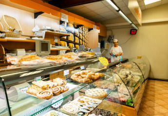 Bakery in het mobil home Cottage «Cesenatico» in Italië met gebak en medewerker achter de toonbank.