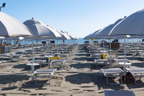 Playa vacía con hileras de sombrillas y tumbonas junto al mar, tomada en Cottage Cesenatico, Italia.