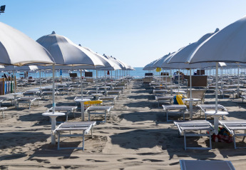 Playa vacía con hileras de sombrillas y tumbonas junto al mar, tomada en Cottage Cesenatico, Italia.