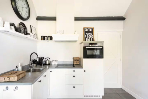 Lichte, moderne keuken van Holiday home De Vlonder met koffiemachine, wandklok en witte kasten.