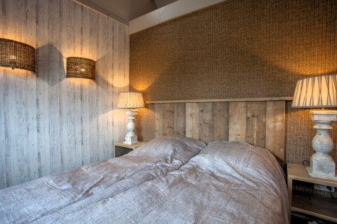 Cozy bedroom at Holiday home De Vlonder in the Netherlands, featuring rustic wooden decor and warm lighting.