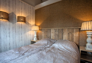 Sfeervolle slaapkamer bij Holiday home De Vlonder, Nederland, met houten interieur en warm licht.