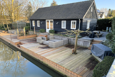 Chaletet Holiday home De Vlonder i Holland med en træterrasse, havesæder og udsigt til kanalen.