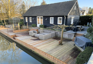 Vakantiehuis De Vlonder in Nederland met houten vlonder, tuinmeubilair en uitzicht op het water.