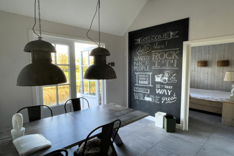 Spiseområde i chalet 'Holiday home De Vlonder' i Holland med tavlevæg og moderne belysning.