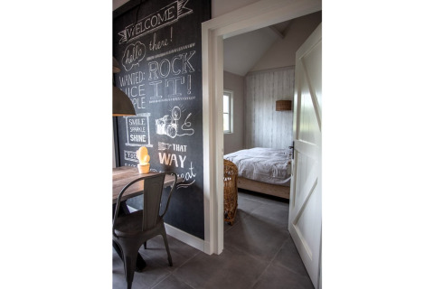 Ingang naar slaapkamer in chalet Holiday home De Vlonder, met een krijtbordmuur met creatieve teksten.