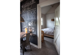 Ingang naar slaapkamer in chalet Holiday home De Vlonder, met een krijtbordmuur met creatieve teksten.