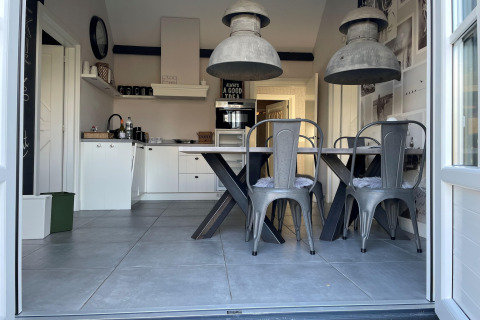Moderne køkken og spisestue i chaletet 'Holiday home De Vlonder' med industrielle lamper og grå stole.