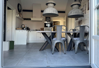 Moderne køkken og spisestue i chaletet 'Holiday home De Vlonder' med industrielle lamper og grå stole.