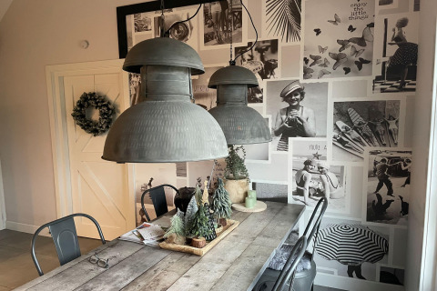 Eethoek in chalet De Vlonder, Nederland, met zwart-witte fotowand en houten tafel met decoratie.