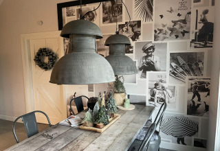 Eethoek in chalet De Vlonder, Nederland, met zwart-witte fotowand en houten tafel met decoratie.