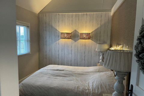 Slaapkamer in Holiday home De Vlonder, Nederland, met sfeerverlichting, tweepersoonsbed en raam.