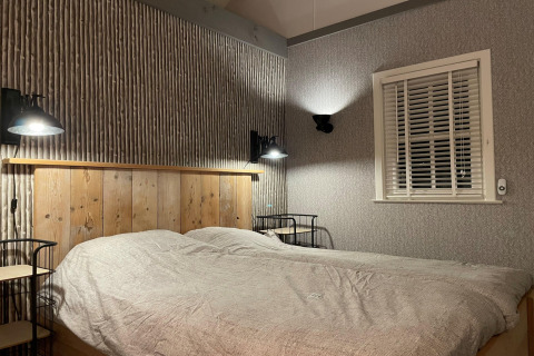 Slaapkamer in chalet 'Holiday home De Vlonder' in Nederland met tweepersoonsbed en wandlampen.