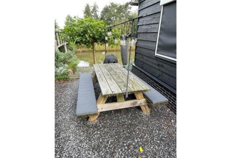 Picknicktafel met banken bij vakantiehuis De Vlonder in Nederland, met tuin en grind eromheen.