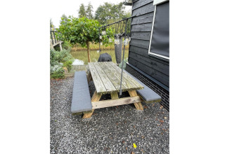 Picknicktafel met banken bij vakantiehuis De Vlonder in Nederland, met tuin en grind eromheen.