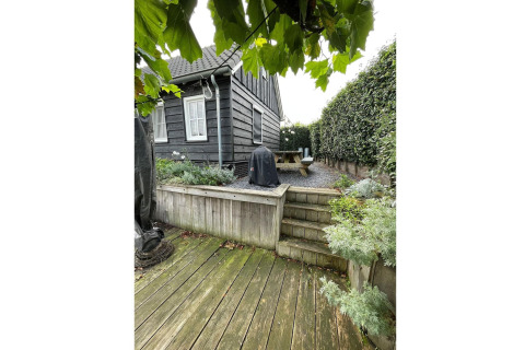 Udendørs træterrasse og haveområde ved Holiday home De Vlonder chalet, med grønne planter i Holland.