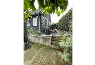 Udendørs træterrasse og haveområde ved Holiday home De Vlonder chalet, med grønne planter i Holland.
