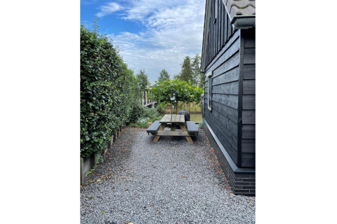 Udendørs område ved chalet 'Holiday home De Vlonder' i Holland med bænk, grus og grøn hæk.