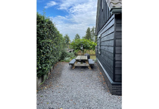 Outdoor area at chalet 'Holiday home De Vlonder' in the Netherlands with picnic table and hedge.