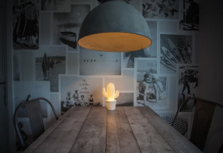 Et hyggeligt træbord med en glødende kaktuslampe under en stor lampe i et moderne chalet.