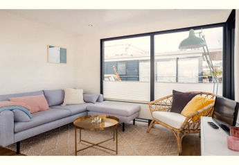 Salon du houseboat Agua Dolce aux Pays-Bas avec grandes fenêtres, canapé confortable et décoration moderne.