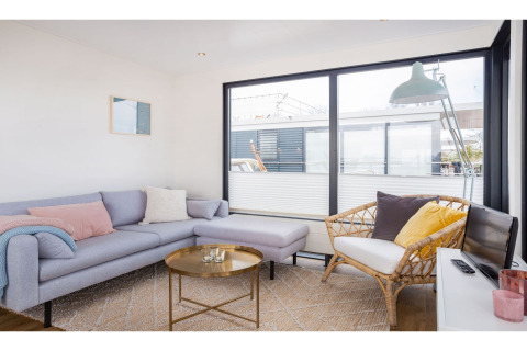 Sala de estar en la casa flotante Agua Dolce en Países Bajos, con ventanas grandes y decoración moderna.