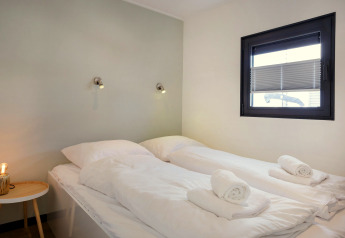 Chambre moderne sur la péniche «Agua Dolce» aux Pays-Bas avec deux lits simples et serviettes roulées.