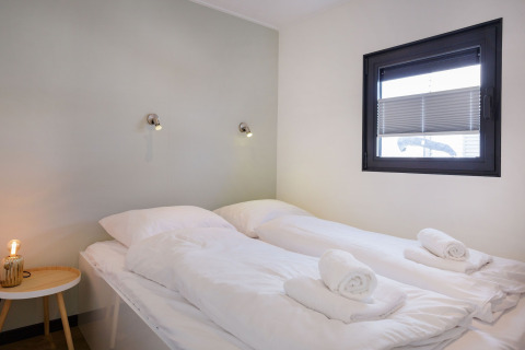 Dormitorio moderno en la casa flotante «Agua Dolce» en los Países Bajos, con dos camas y toallas blancas.
