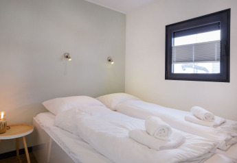 Chambre moderne sur la péniche «Agua Dolce» aux Pays-Bas avec deux lits simples et serviettes roulées.