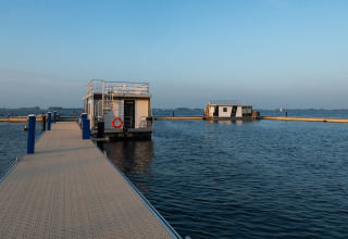 Foto des Hausboots 'Agua Dolce' an einem Steg in den Niederlanden, umgeben von ruhigem Wasser und Himmel.