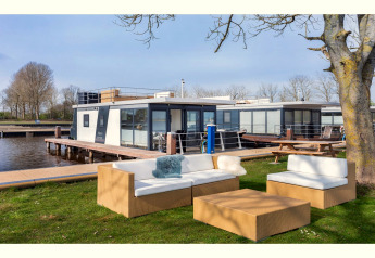 Coin salon extérieur devant la péniche «Agua Dolce» aux Pays-Bas, avec mobilier moderne au bord de l’eau.