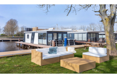 Zona de estar al aire libre junto a la casa flotante «Agua Dolce» en Países Bajos, con muebles modernos.