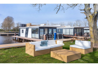 Zona de estar al aire libre junto a la casa flotante «Agua Dolce» en Países Bajos, con muebles modernos.