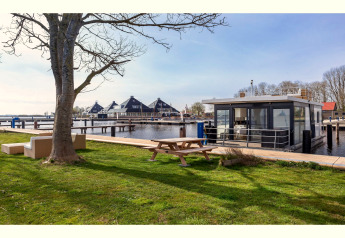 Hausboot «Agua Dolce» in den Niederlanden am Wasser, Picknicktisch und Sofas im Vordergrund.
