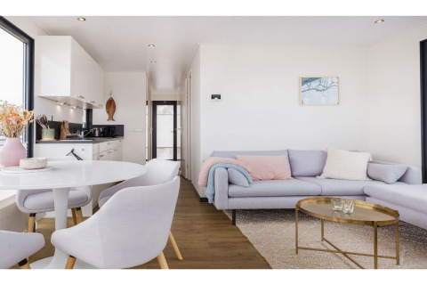Modernes Wohnzimmer und Küche im Hausboot 'Agua Dolce' in den Niederlanden mit hellen Möbeln.