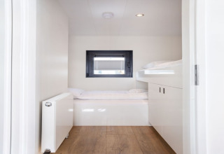 Dormitorio luminoso y moderno con literas y suelo de madera en la casa flotante 'Agua Dolce' en Países Bajos.