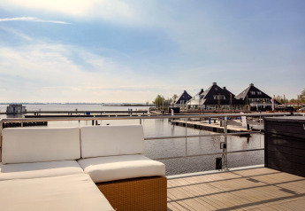 Vue depuis la péniche «Agua Dolce» aux Pays-Bas, terrasse aménagée et bâtiments au bord du port.