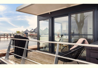 Terrasse på husbåd 'Agua Dolce' i Holland med moderne havemøbler og udsigt over vandet.