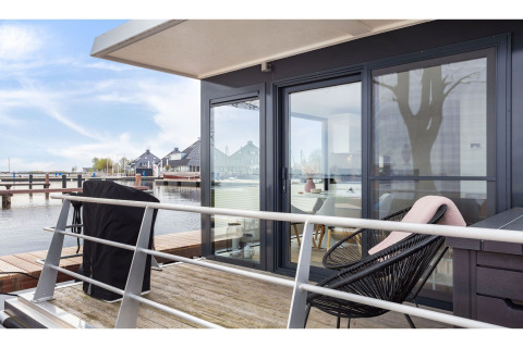 Terrasse des Hausboots 'Agua Dolce' in den Niederlanden mit Sitzgelegenheiten und Blick aufs Wasser.