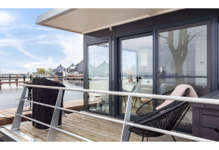 Terrasse des Hausboots 'Agua Dolce' in den Niederlanden mit Sitzgelegenheiten und Blick aufs Wasser.
