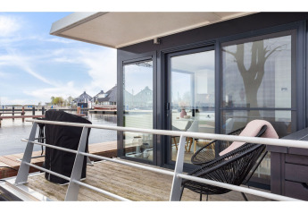 Terrasse du bateau-maison 'Agua Dolce' aux Pays-Bas avec assises modernes et vue sur l’eau.