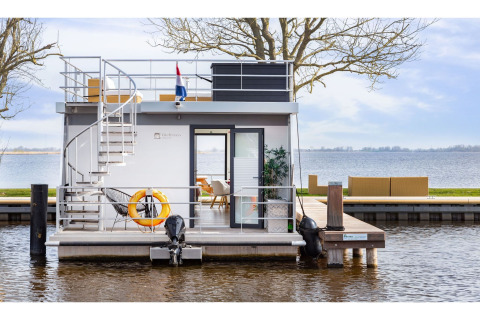 Das moderne Hausboot 'Agua Dolce' liegt in den Niederlanden mit Sonnendeck und Seeblick vor Anker.