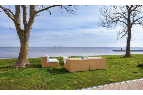Outdoor-Loungebereich mit Sofas am Seeufer, gesehen vom Hausboot 'Agua Dolce' in den Niederlanden.