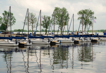 Voiliers amarrés près de la houseboat «Agua Dolce» aux Pays-Bas, avec arbres en arrière-plan.
