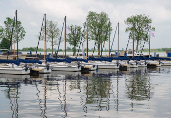 Voiliers amarrés près de la houseboat «Agua Dolce» aux Pays-Bas, avec arbres en arrière-plan.