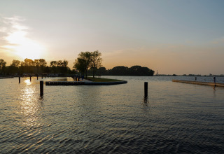 Atardecer en el lago visto desde Houseboat 'Agua Dolce' en los Países Bajos, con agua tranquila y árboles.