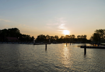 Sonnenuntergang am Wasser bei Hausboot «Agua Dolce» in den Niederlanden mit Bäumen und Anlegestellen.