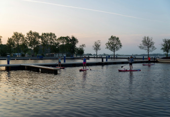 Menschen paddeln auf Paddleboards bei Sonnenuntergang bei Hausboot «Agua Dolce» in den Niederlanden.