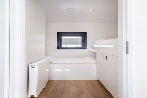 Helles Schlafzimmer mit Etagenbetten und Fenster auf dem Hausboot „Agua Dolce“ in den Niederlanden.